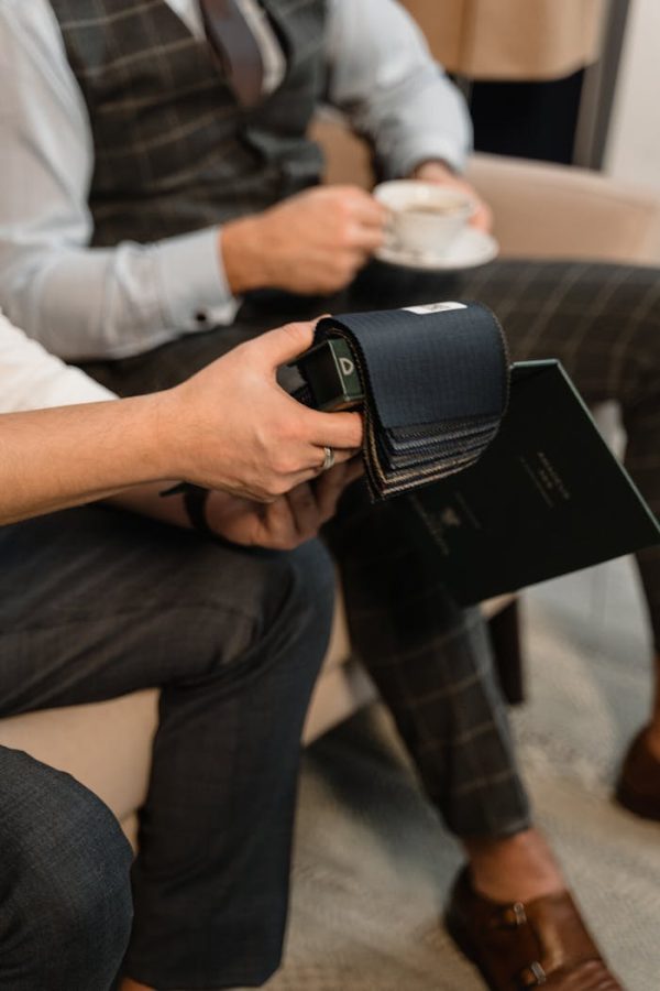 Tailor showcases fabric samples to client in a stylish, professional setting.